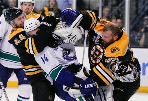 Late in the game, Bruins goalie Tim Thomas got physical against Alex Burrows, center, and the Vancouver Canucks. Boston defenseman Dennis Seidenerg bolds Burrows Back.