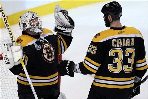 Bruins goaltender Tim Thomas celebrates his team's 5-2 win over the Vancouver Canucks with teammate Zdeno Chara.