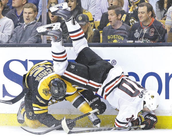 Chicago Blackhawks center Patrick Sharp (10) is upended along the wall by Boston Bruins defenseman Johnny Boychuk during the third period in Game 4 of the Stanley Cup Finals.